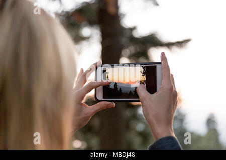 Frau mit Kamera Handy fotografiert Sonnenuntergang Stockfoto