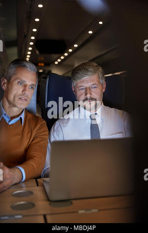 Unternehmer bei der Laptop arbeiten an Personenzug in der Nacht Stockfoto