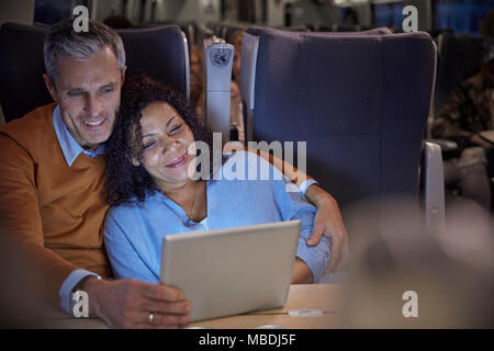 Zärtlich Paar beobachten Film auf digital Tablet auf Personenzug in der Nacht Stockfoto