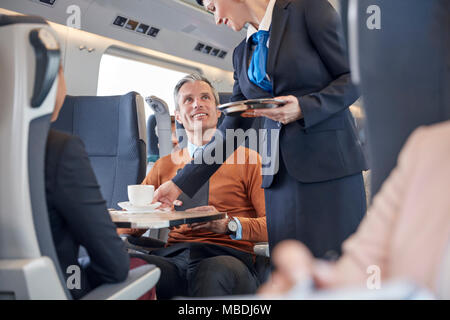 Attendant Kaffee zu Geschäftsmann auf Personenzug Stockfoto