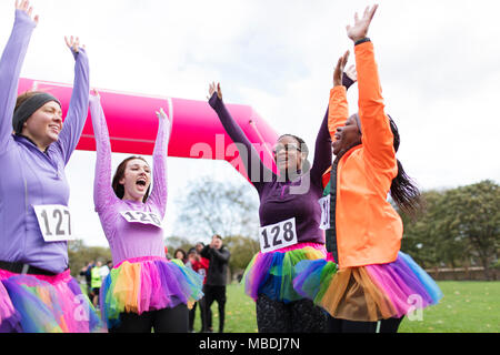 Begeisterte Läuferinnen mit tütü Jubeln, Feiern im spendenlauf Finish Line Stockfoto