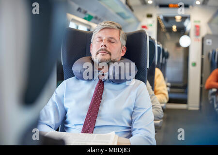 Müde Geschäftsmann mit Nackenkissen schlafen auf Personenzug Stockfoto