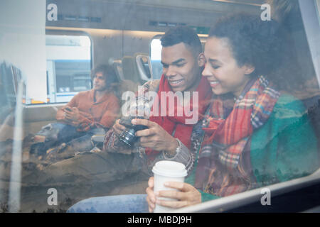 Junges Paar mit Kaffee an Digitalkamera auf Fenster auf Personenzug Stockfoto