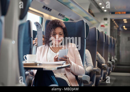 Geschäftsfrau und Musikhören mit Kopfhörern und Smart Phone auf Personenzug Stockfoto