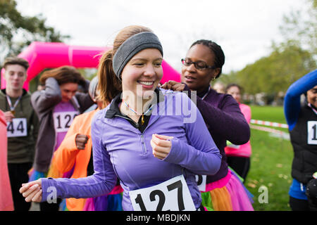 Frau pinning Marathon bib auf Freund an der Nächstenliebe laufen im Park Stockfoto