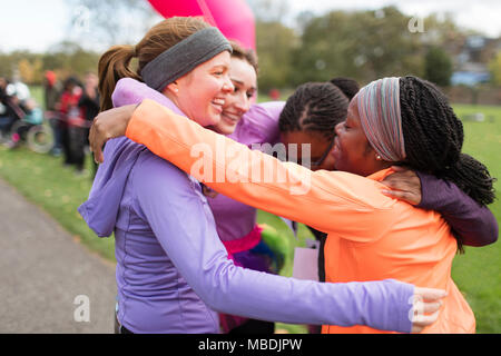 Happy Läuferinnen umarmen bei spendenlauf Finish Line, Feiern Stockfoto