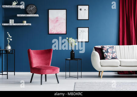 Rote Sessel und Poster in Blau Wohnzimmer mit Sofa neben einem Tisch mit Blumen Stockfoto