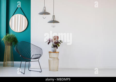 Anlage auf Gold Tisch neben schwarzen Sessel im Wohnzimmer minimalistischen Interieur mit Lampen und runden Spiegel Stockfoto