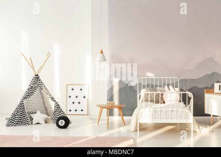 White's Kind Bett gegen eine Wand mit Berg Tapete im Schlafzimmer Einrichtung mit gemusterten Zelt Stockfoto