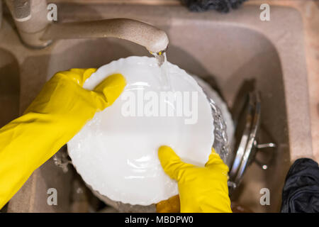 Die Frau, die Hände in den Handschuhen Teller waschen. closeup. Stockfoto