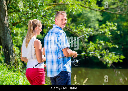 Junges Paar Fischen oder Angeln am Fluss Ufer Stockfoto