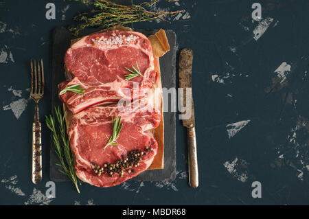 Schneiden von Fleisch zum Grillen auf Holz Schneidebrett mit Lorbeerblatt, Rosmarin für die Marinade in einer rustikalen Stil. Kopieren Sie Platz. Ein horizontaler Rahmen. Stockfoto