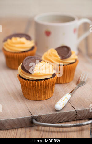 Bunte Schokolade orange Cupcakes auf einem Teller mit einer Tasse Kaffee Stockfoto