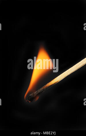 Brennende Streichholz vor einem schwarzen Hintergrund Stockfoto