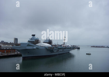 Mit Blick auf den Hafen von Royal Navy HMS Queen Elizabeth unter Wartung, mit Polizei Patrouillenboote auf der Hut in Portsmouth, Großbritannien Stockfoto