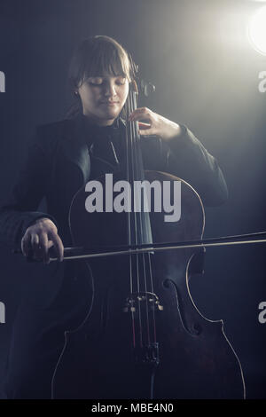 Cellist spielt klassische Musik am Cello auf schwarzem Hintergrund Stockfoto