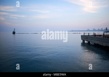 Jetty und Wellenbrecher mit Marker Boje auf einem ruhigen See Michigan bei Sonnenuntergang mit einem rosa Farbton zu den Himmel Stockfoto