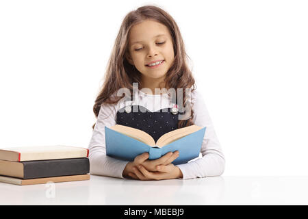 Kleines Mädchen sitzen an einem Tisch und ein Buch auf weißem Hintergrund Stockfoto