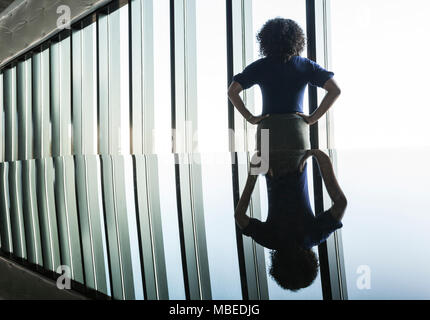 Schwarz Geschäftsfrau spiegelt sich auf dem Glas in einem Büro vor einer Bank von Windows. Stockfoto