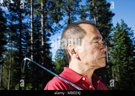 Ein älterer Golfspieler sind Sie bereit für den nächsten Schuß auf einen Golfplatz zu nähern. Stockfoto