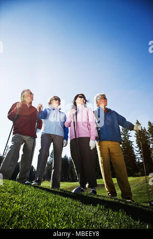 Zwei junge senior Golf spielende Paare auf dem Kurs und bereit zu spielen. Stockfoto