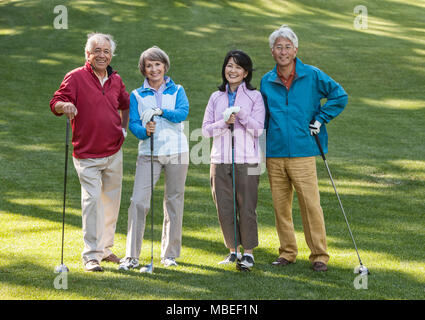 Zwei junge senior Golf spielende Paare auf dem Kurs und bereit zu spielen. Stockfoto