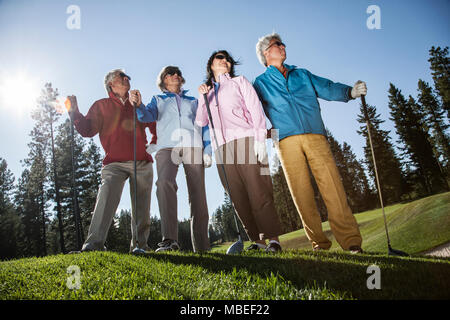 Zwei junge senior Golf spielende Paare auf dem Kurs und bereit zu spielen. Stockfoto