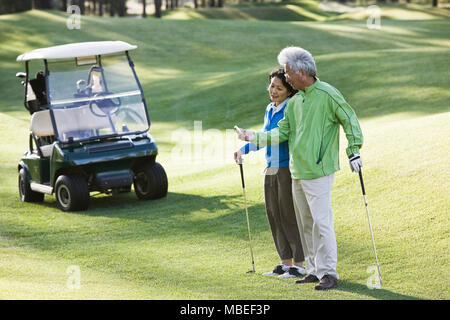 Eine asiatische Senior paar Kontrolle des Yards das Flag für den nächsten Schuss. Stockfoto