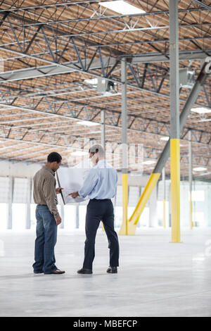 Zurück man Inhaber der neuen Lager- und kaukasischen Mann Architekten über blue print Pläne der neuen Innenausstattung. Stockfoto