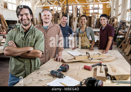 Team von multi-ethnischen Arbeiter neben einem Arbeitsplatz in einem großen Wald, die Fabrik steht. Stockfoto