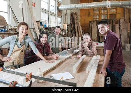 Team von multi-ethnischen Arbeiter neben einem Arbeitsplatz in einem großen Wald, die Fabrik steht. Stockfoto