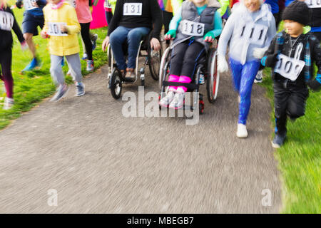 Menschen im Rollstuhl und Läufern an Charity Rennen verschieben Stockfoto