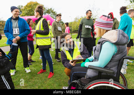 Frau im Rollstuhl in mit Freiwilliger an Charity Rennen in Park Stockfoto