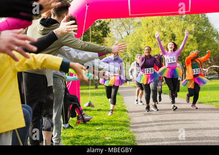 Begeisterte Läuferinnen mit tütü kurz vor der Ziellinie an der Nächstenliebe laufen im Park Stockfoto