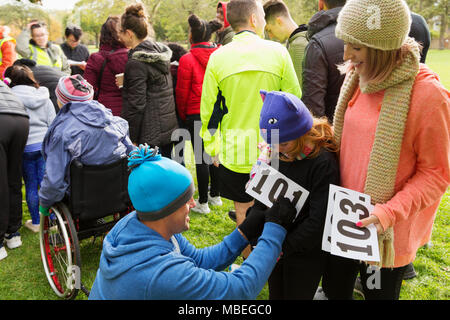 Vater runner pinning Marathon bib auf die Tochter, die an der Spendenaktion in Park Stockfoto