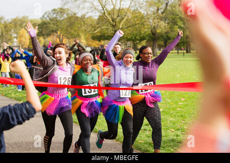 Begeisterte Läuferinnen mit tütü Nächstenliebe Kreuzung laufen Finish Line in Park, Feiern Stockfoto