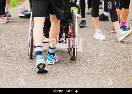 Mann Schieberollstuhl auf überfüllten Pfad Stockfoto