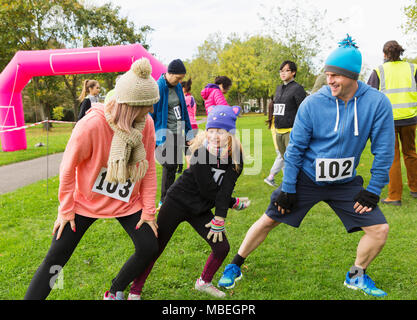 Familie Läufer Stretching, Vorbereitung für spendenlauf in Park Stockfoto