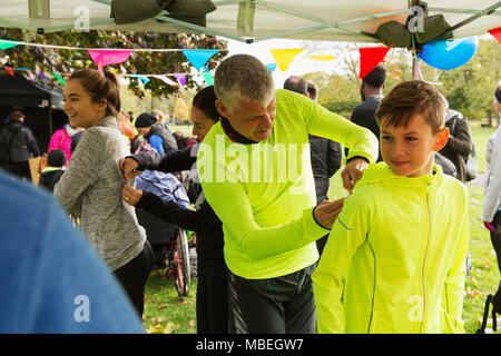 Vater pinning Marathon bib auf Sohn an der Spendenaktion in park-Zelt Stockfoto