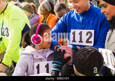 Familie Läufer prüfen smart Watch at Charity Run Start Stockfoto