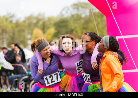 Happy Läuferinnen umarmen bei spendenlauf Finish Line Stockfoto