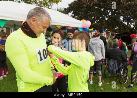 Familie Läufer pinning Marathon Lätzchen, Vorbereitung für spendenlauf in Park Stockfoto