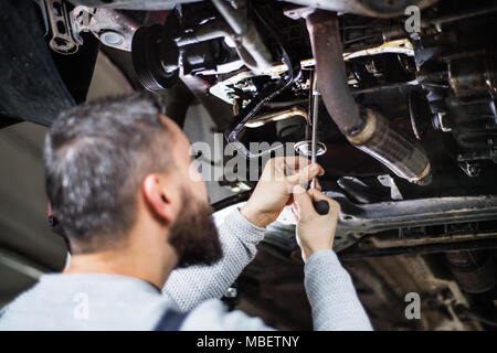 Reifer mann Mechaniker reparieren ein Auto in eine Garage. Bis zu schließen. Stockfoto