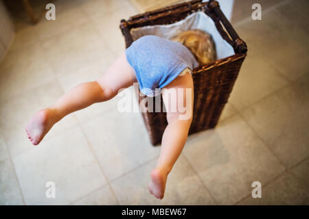 Little Boy in einer gefährlichen Situation im Bad. Ein Kleinkind in einem Wäschekorb, Beine heraus haften. Stockfoto