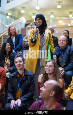 Lächelnde Frau im hijab im Gespräch mit Mikrofon in Konferenz Publikum Stockfoto