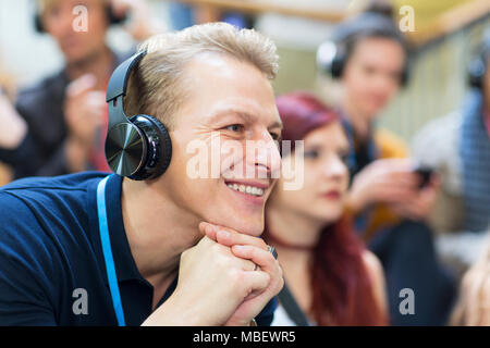 Lächelnd Geschäftsmann mit Kopfhörern in der Konferenz Publikum Stockfoto