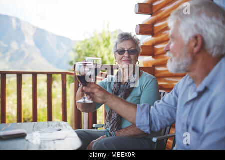 Active Senior Paar toasten Rotwein Gläser auf dem Balkon Stockfoto