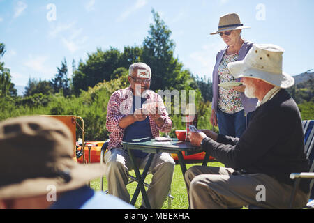 Verspielte Active Senior Freunden Karten spielt im sonnigen Sommer Campingplatz Stockfoto