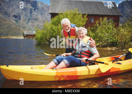 Porträt Lächeln Active Senior paar Kajakfahren auf sonnigen Sommer See Stockfoto