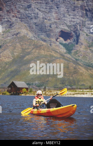 Active Senior mann Kajak auf sonnigen Sommer See Stockfoto